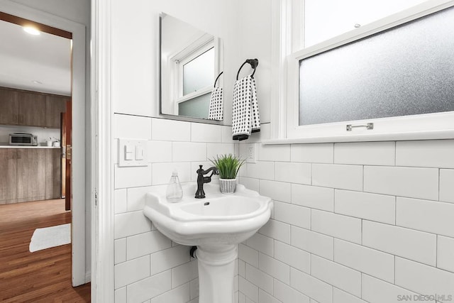 bathroom featuring wood-type flooring, sink, and tile walls