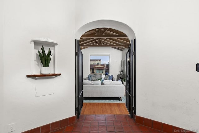 corridor featuring lofted ceiling with beams and dark tile patterned flooring