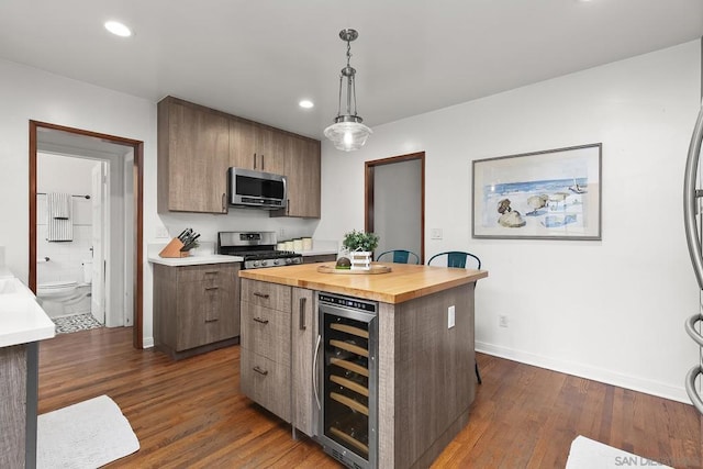 kitchen featuring appliances with stainless steel finishes, hanging light fixtures, a center island, wine cooler, and wood counters