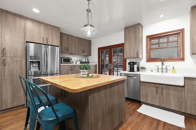 kitchen with french doors, dark wood-type flooring, sink, decorative light fixtures, and appliances with stainless steel finishes