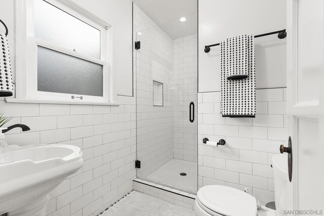 bathroom featuring sink, a shower with door, and tile walls