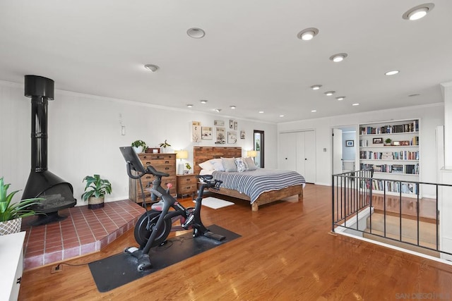 bedroom featuring hardwood / wood-style flooring, ornamental molding, and a wood stove