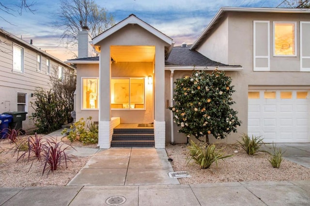 exterior entry at dusk featuring a garage