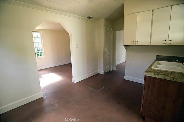 kitchen with white cabinetry, ornamental molding, and sink