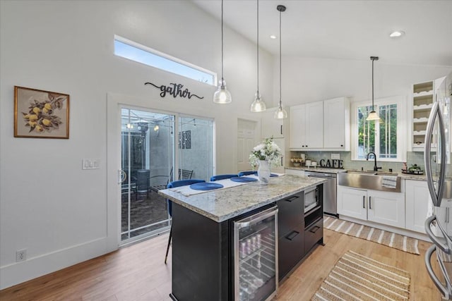 kitchen featuring white cabinets, a center island, sink, and beverage cooler