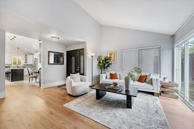 living room featuring high vaulted ceiling and light wood-type flooring