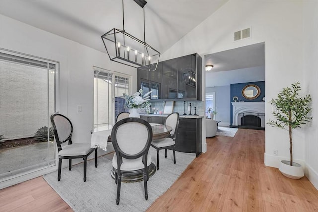 dining room featuring vaulted ceiling, light hardwood / wood-style flooring, and a notable chandelier