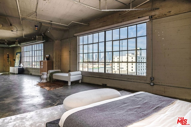 bedroom featuring concrete flooring and multiple windows