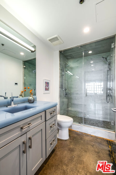 bathroom with walk in shower, vanity, toilet, and concrete flooring