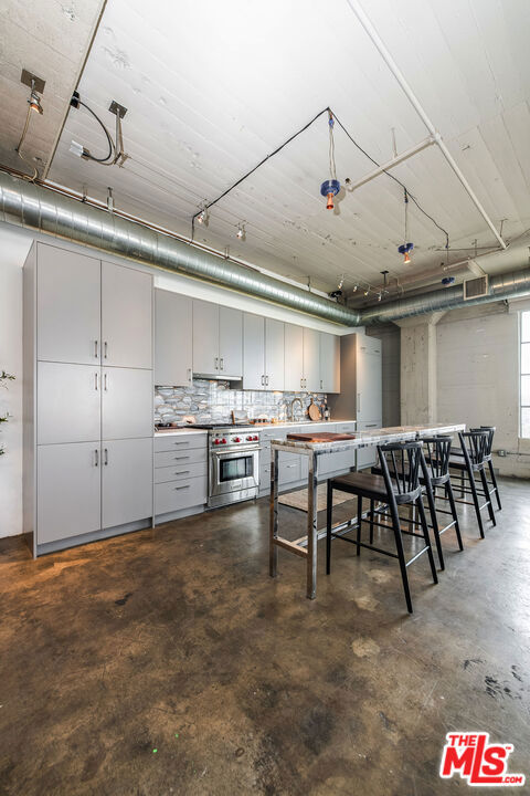 kitchen featuring tasteful backsplash, high end stove, and gray cabinetry