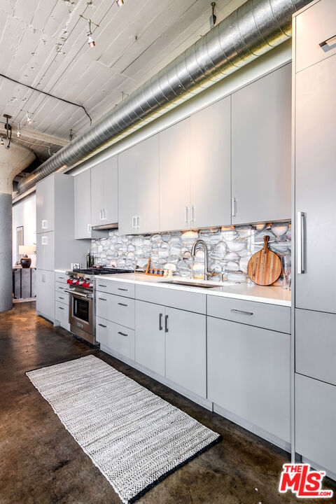 kitchen with decorative backsplash, sink, and high end stove