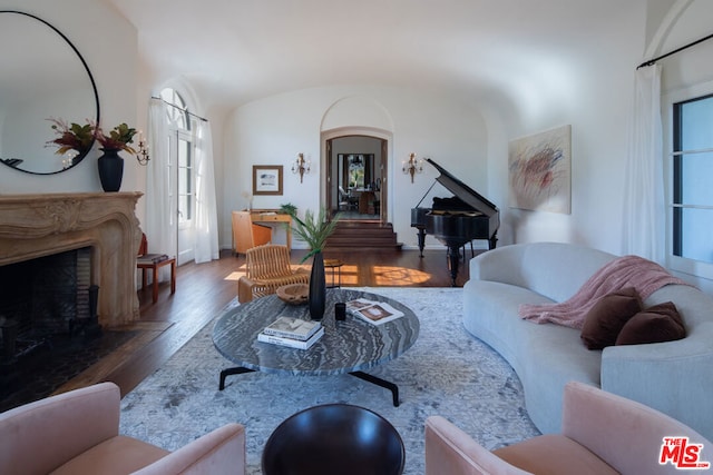 living room featuring lofted ceiling, dark hardwood / wood-style floors, and a fireplace