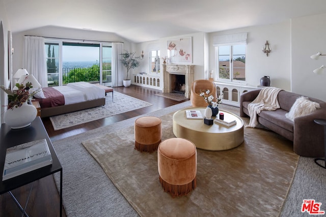 living room with dark wood-type flooring, a healthy amount of sunlight, and vaulted ceiling