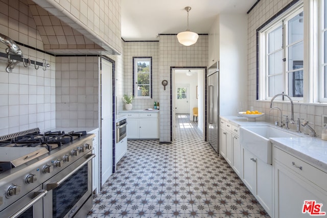 kitchen with white cabinetry, high end appliances, tile walls, and decorative light fixtures