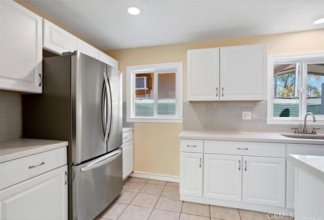 kitchen with white cabinetry, sink, light tile patterned floors, and stainless steel fridge