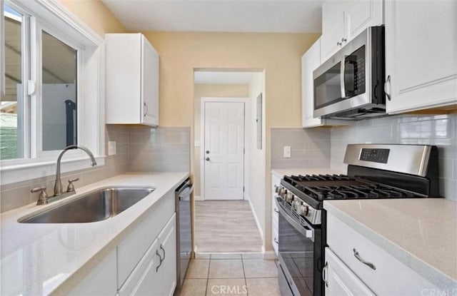 kitchen featuring stainless steel appliances, white cabinetry, sink, and tasteful backsplash