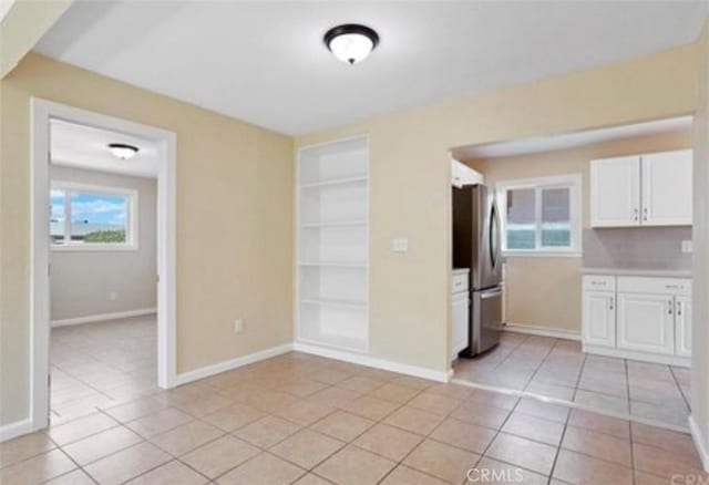 kitchen with stainless steel refrigerator, white cabinetry, built in features, and light tile patterned floors