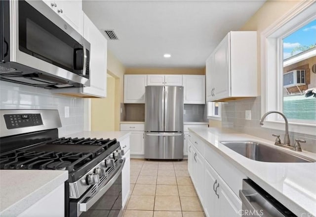 kitchen featuring sink, light tile patterned floors, stainless steel appliances, decorative backsplash, and white cabinets