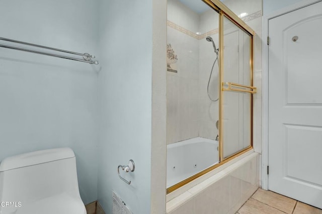 bathroom featuring tile patterned floors, enclosed tub / shower combo, and toilet