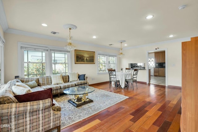 living room with wood-type flooring, ornamental molding, and a chandelier