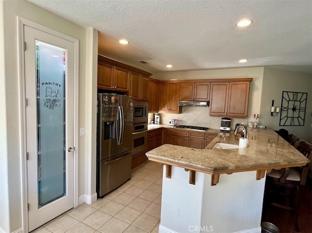 kitchen featuring sink, a kitchen breakfast bar, light tile patterned floors, kitchen peninsula, and stainless steel appliances