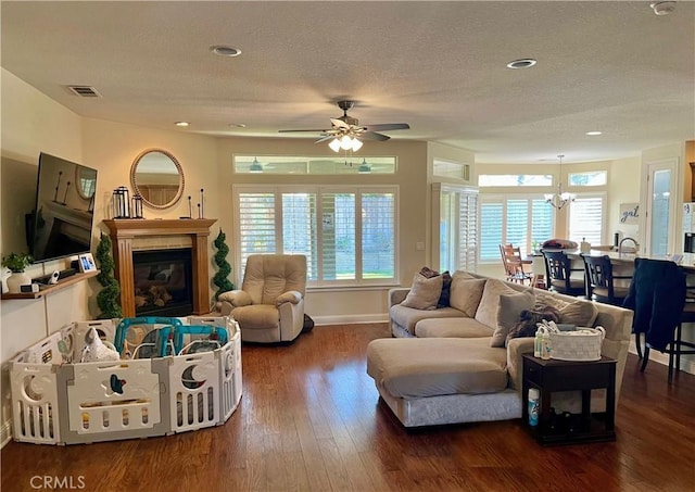 living room with dark hardwood / wood-style floors, ceiling fan with notable chandelier, and a textured ceiling