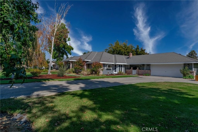 ranch-style home featuring a chimney, a garage, a front yard, and driveway