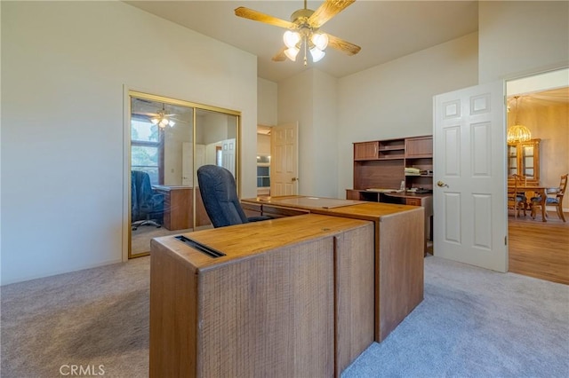 carpeted office with ceiling fan and a towering ceiling