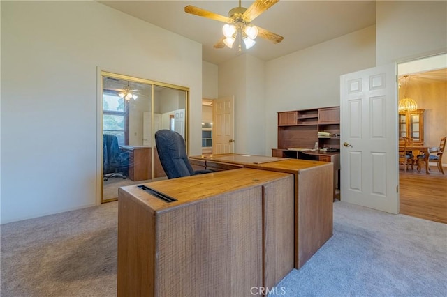 office with ceiling fan, a high ceiling, and light carpet