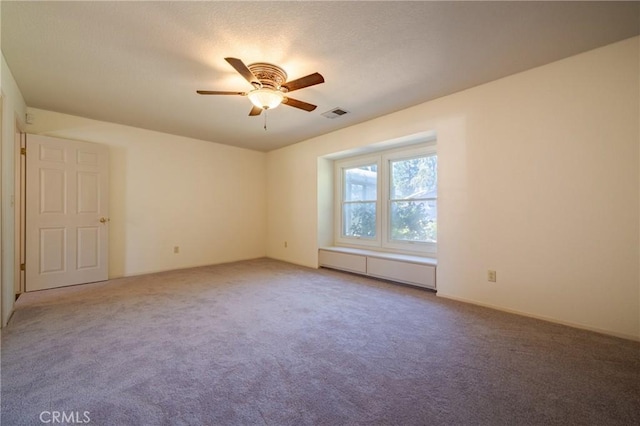 carpeted spare room featuring visible vents, a baseboard radiator, and a ceiling fan