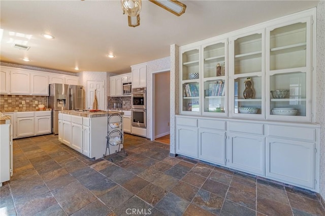 kitchen with decorative backsplash, appliances with stainless steel finishes, visible vents, and white cabinets