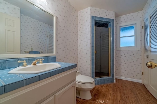 full bath with toilet, wallpapered walls, a stall shower, and wood finished floors