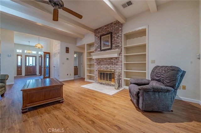 living area featuring wood finished floors, beam ceiling, and visible vents