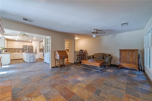 living room with ceiling fan and a textured ceiling