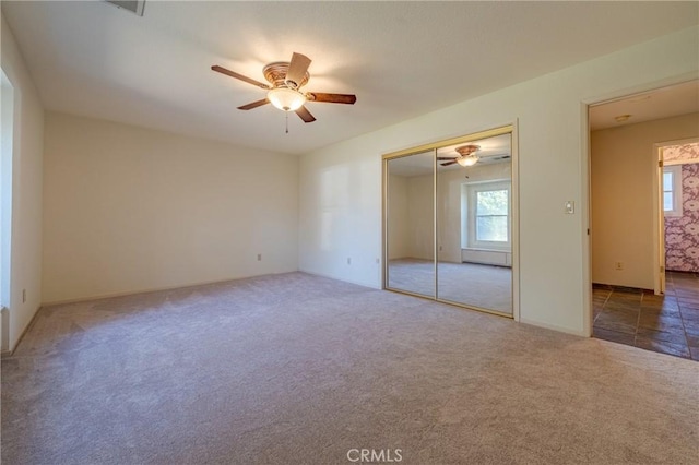 unfurnished bedroom with dark carpet, a closet, and ceiling fan