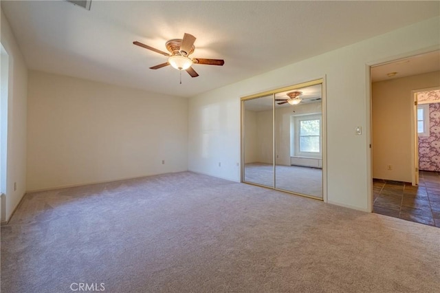 unfurnished bedroom with carpet flooring, a closet, and a ceiling fan
