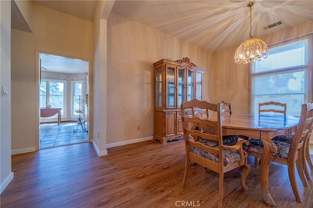 dining room featuring a chandelier, visible vents, baseboards, and wood finished floors