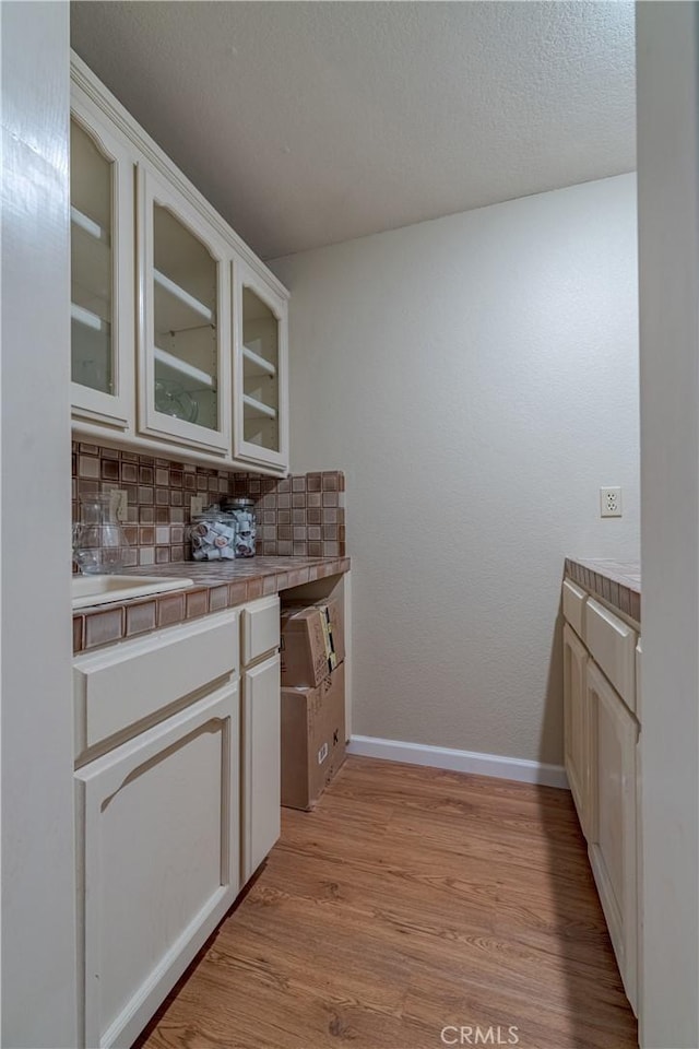 bar with tasteful backsplash, baseboards, and light wood-style floors