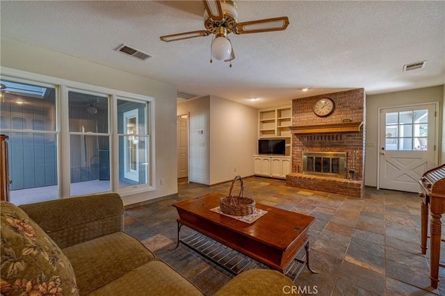 living room with visible vents, ceiling fan, and stone tile floors