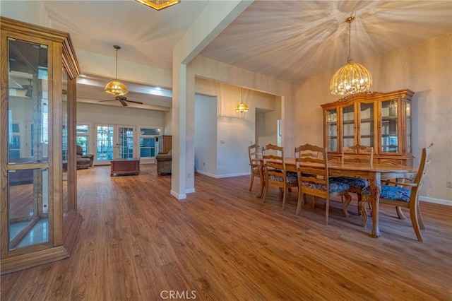 dining area with dark wood-type flooring, ceiling fan with notable chandelier, and french doors