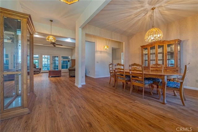 dining area featuring baseboards, wood finished floors, and ceiling fan with notable chandelier