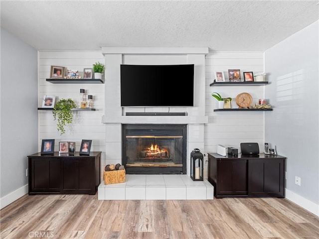 living room featuring a fireplace, a textured ceiling, and light wood-type flooring