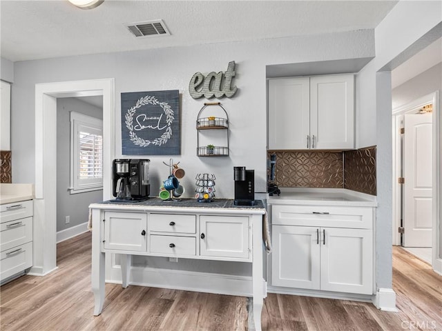 kitchen featuring tasteful backsplash, white cabinets, and light wood-type flooring