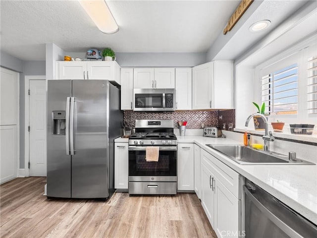 kitchen featuring stainless steel appliances, sink, white cabinets, and light wood-type flooring