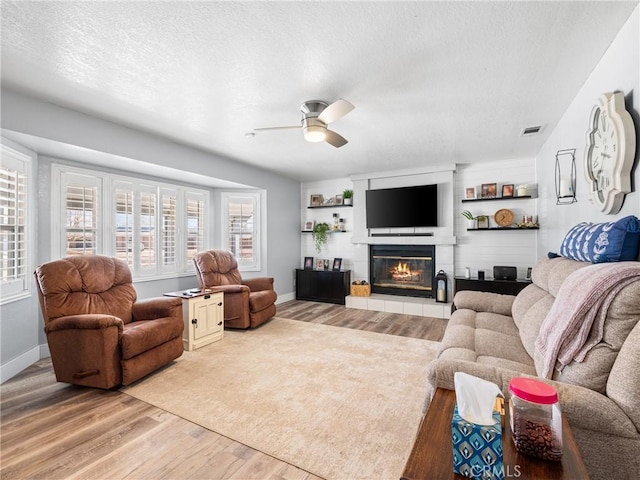 living room with ceiling fan, hardwood / wood-style flooring, and a textured ceiling