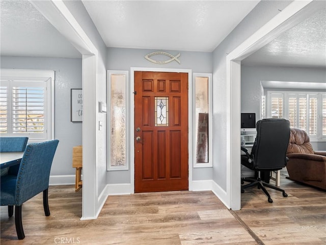 foyer entrance with light hardwood / wood-style floors and a textured ceiling