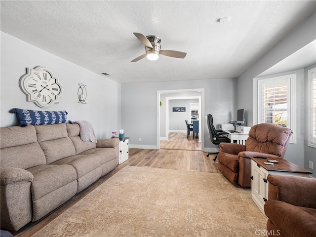 living room featuring ceiling fan, a textured ceiling, and light hardwood / wood-style floors