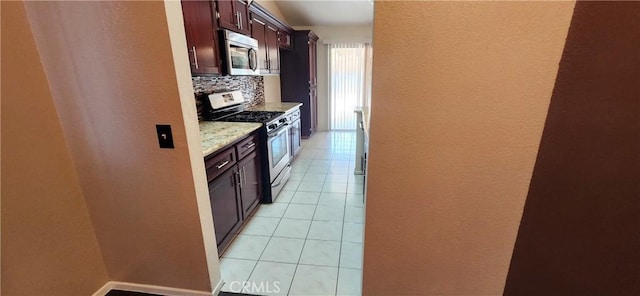 kitchen featuring tasteful backsplash, light tile patterned flooring, light stone countertops, and appliances with stainless steel finishes