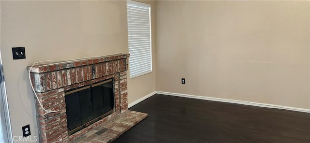 unfurnished living room featuring wood-type flooring and a brick fireplace