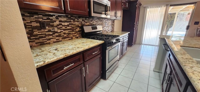 kitchen featuring stainless steel appliances, light tile patterned flooring, light stone countertops, and tasteful backsplash